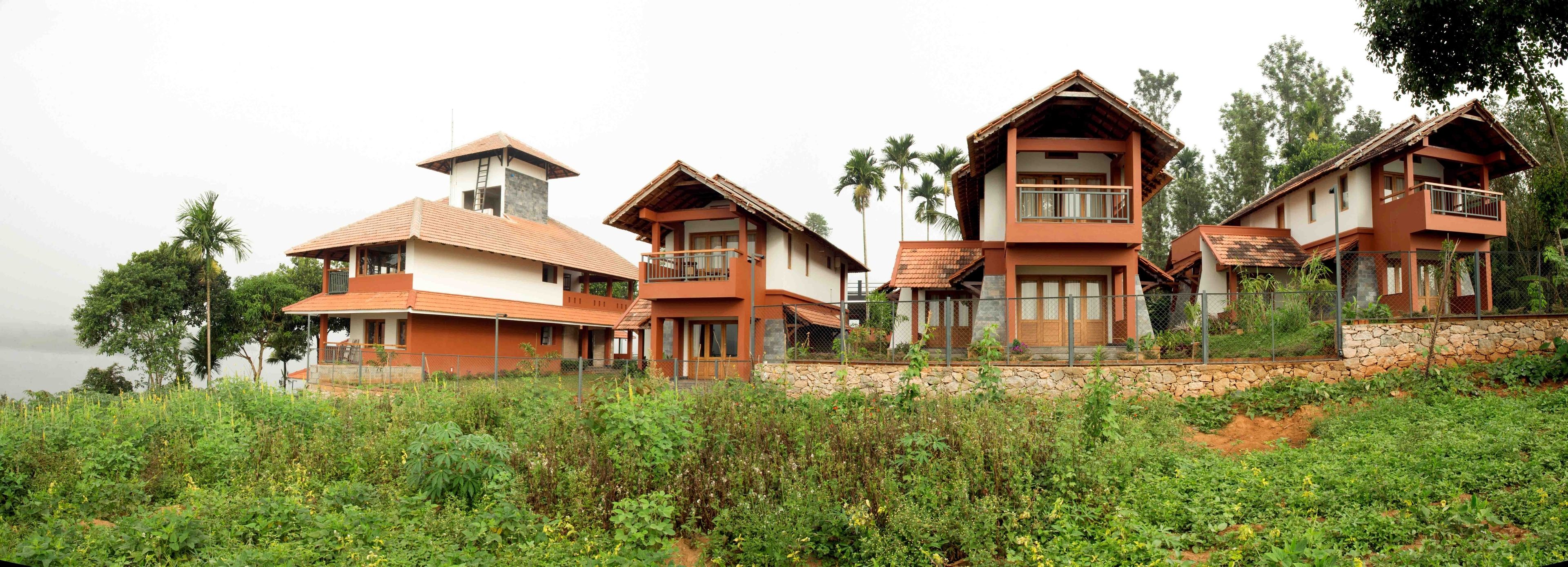 Una hilera de casas modernas de varios pisos con balcones, rodeadas de abundante vegetación y palmeras.
