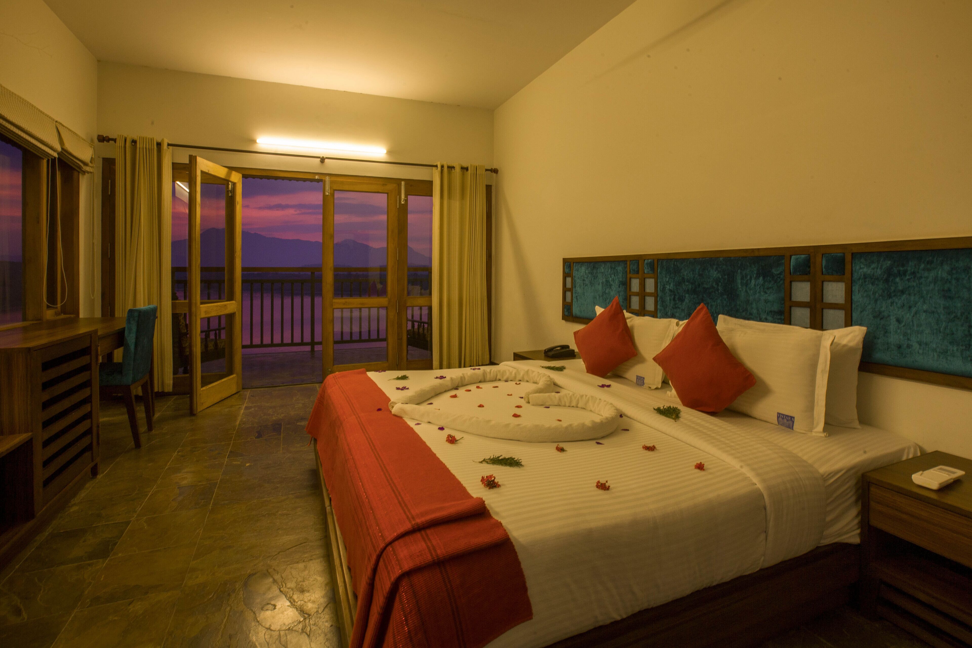 A hotel room with a bed, a desk, and a view of the mountains at sunset.