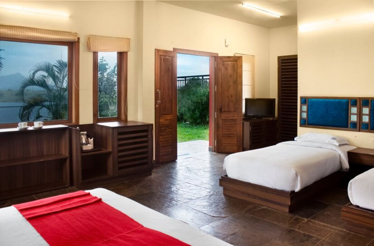 A hotel room with a bed, a desk, a television, and a view of the outdoors.