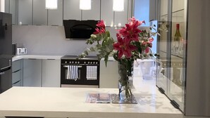A modern kitchen with a central island, pendant lights, and a vase of flowers. - Amazing London (London)