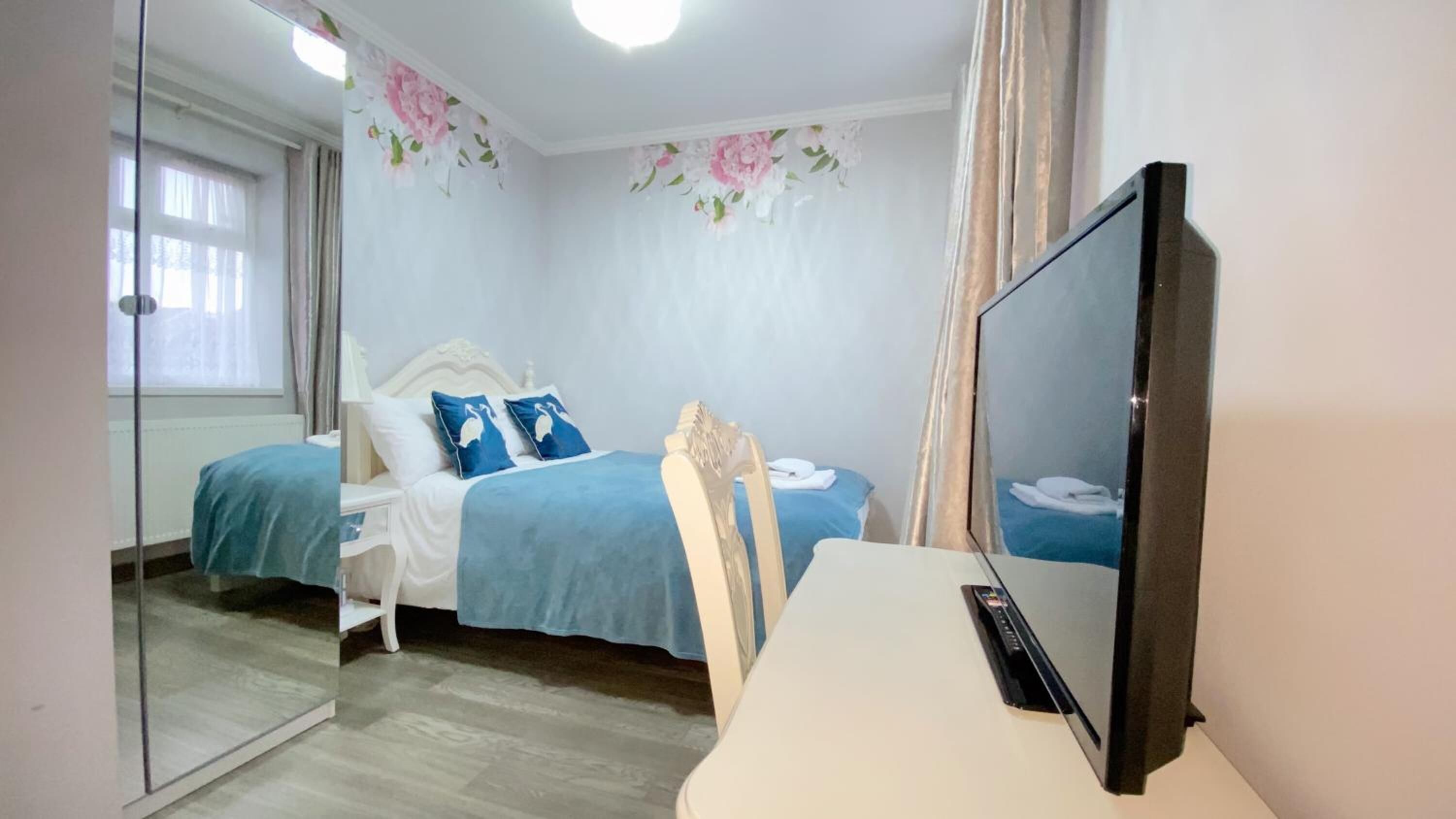 A bedroom with a bed, a chair, a television, and a mirror.
