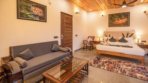 Una habitación de hotel moderna con un sofá, una cama, un sillón mecedora y una mesa de centro de vidrio.
