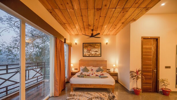 Un dormitorio con una cama grande, techo de madera y vistas a un paisaje nevado a través de un ventanal.