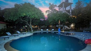 Una piscina con sillones de descanso y una escalera que conduce a un edificio.