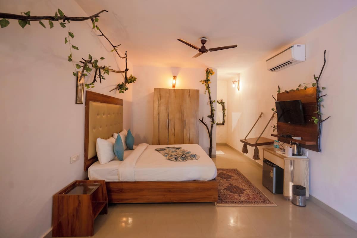 A bedroom with a bed, bedside table, TV, and a small kitchenette.