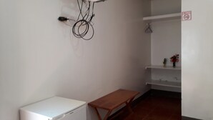 A room with a white refrigerator, a wooden table, and a white shelf unit with a hanging garment. - Hospedaje Mother Fanny (Puerto Villamil)