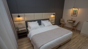 A modern hotel room with a large bed, a bedside table, a chair, and a desk with a lamp. - History Hotel Tbilisi (Tbilisi)