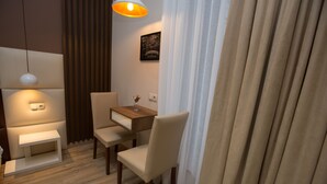 A modern hotel room with a wooden desk, two chairs, a small table, a hanging lamp, and a framed map on the wall. - History Hotel Tbilisi (Tbilisi)