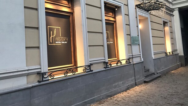 A building facade with three illuminated windows displaying the logo "History Hotel Tbilisi". - History Hotel Tbilisi (Tbilisi)