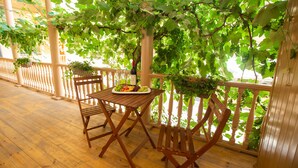 A wooden deck with a table and chairs, surrounded by lush greenery and a wooden railing. - History Hotel Tbilisi (Tbilisi)