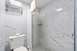 A bathroom with a toilet, a shower, and a towel rack. - Ocean 5 Hotel (Myrtle Beach)