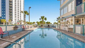 A swimming pool with lounge chairs, a lifeguard stand, and a building with a balcony. - Ocean 5 Hotel (Myrtle Beach)