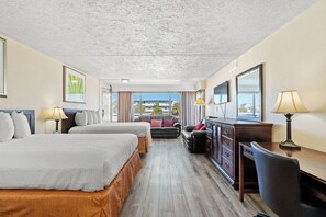 Une chambre d’hôtel avec deux lits, un bureau, une chaise, une commode et une vue sur l’extérieur.