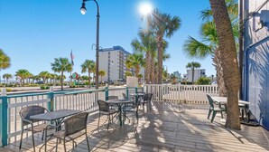 A deck with outdoor seating, palm trees, and a view of a cityscape. - Ocean 5 Hotel (Myrtle Beach)
