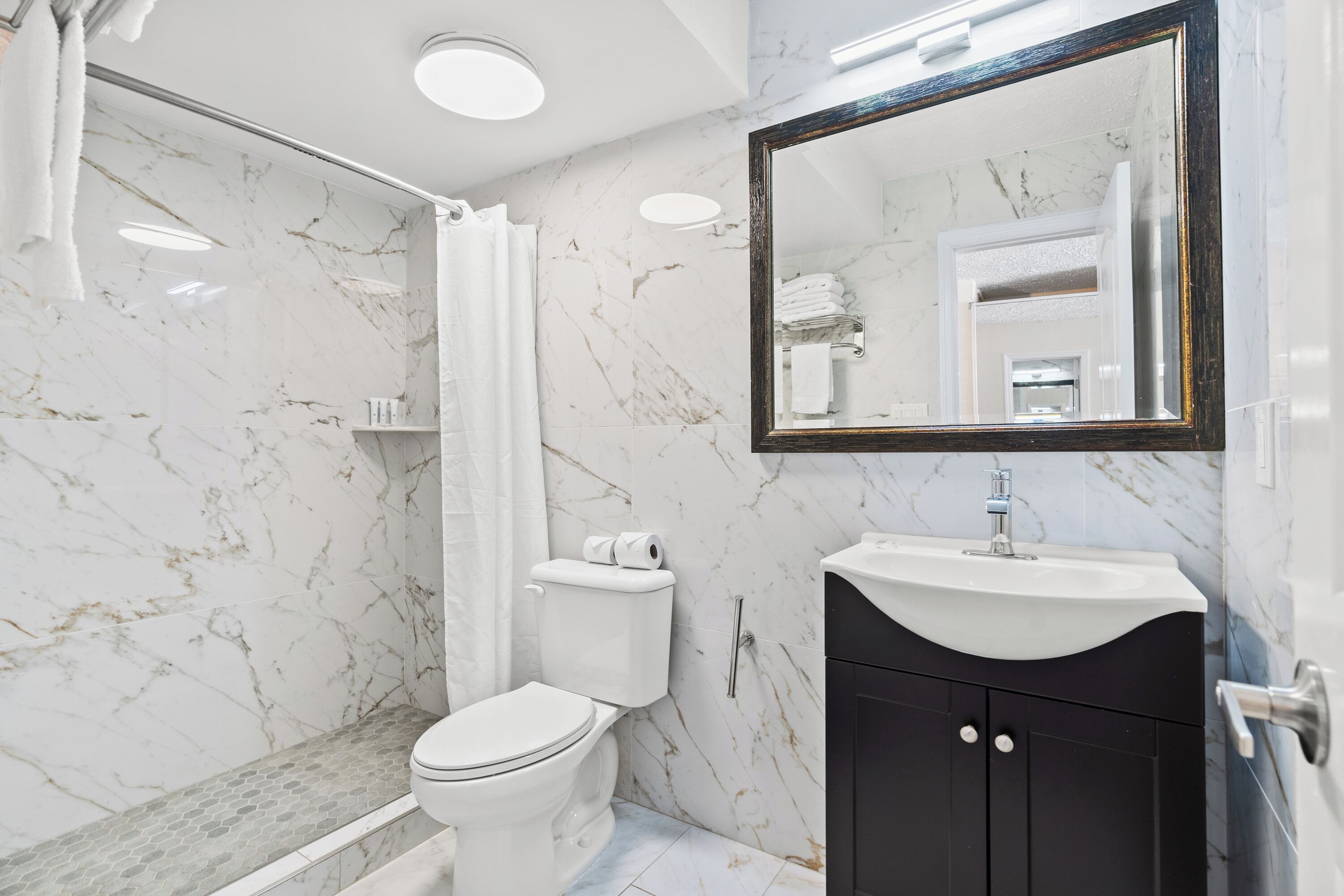 Un baño moderno con inodoro, lavamanos y zona de ducha.