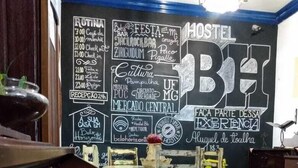 A room with a piano, a chalkboard wall with various writings, and a table with chairs. - Hostel BH (Belo Horizonte)