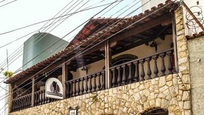 A stone building with a balcony, a sign indicating it's a hostel, and a number 298 on the facade. - Hostel BH (Belo Horizonte)
