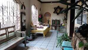 A room with a bed, a bench, and a large window with decorative iron bars. - Hostel BH (Belo Horizonte)
