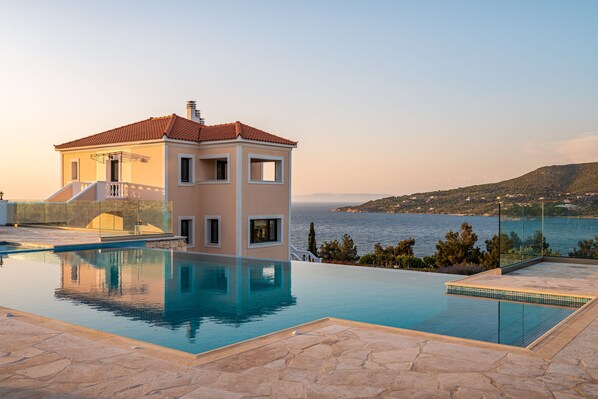 A modern house with a swimming pool, a balcony, and a view of the sea.