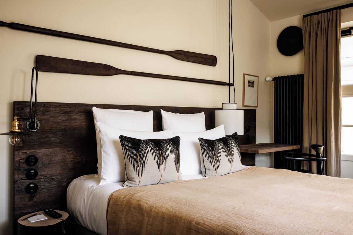 A neatly made bed with a wooden headboard, two bedside tables with lamps, and a round wall decoration.