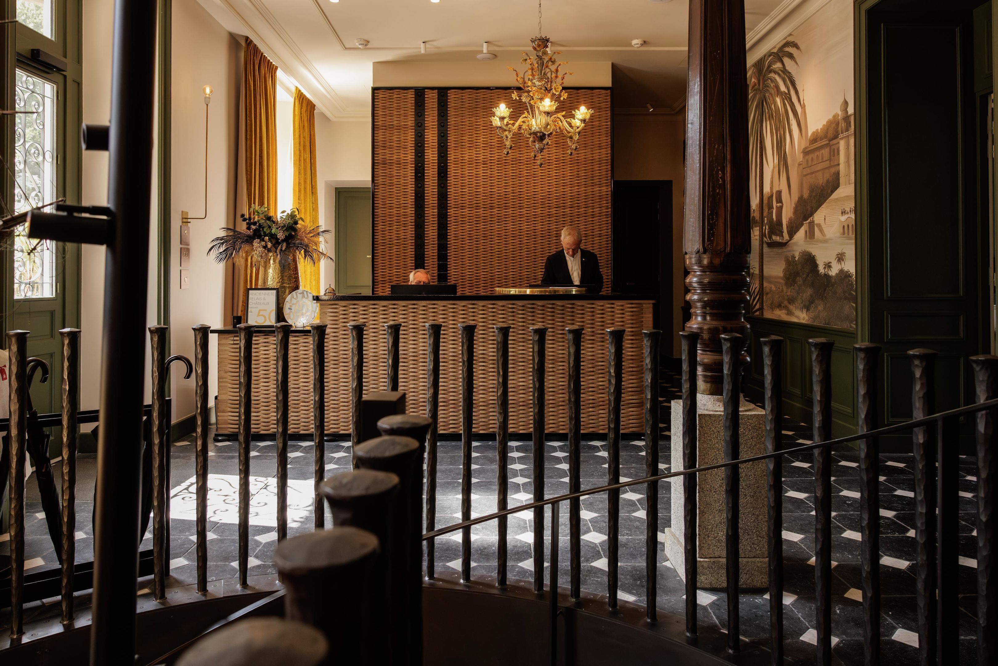A reception area with a check-in counter, a chandelier, and a patterned floor.