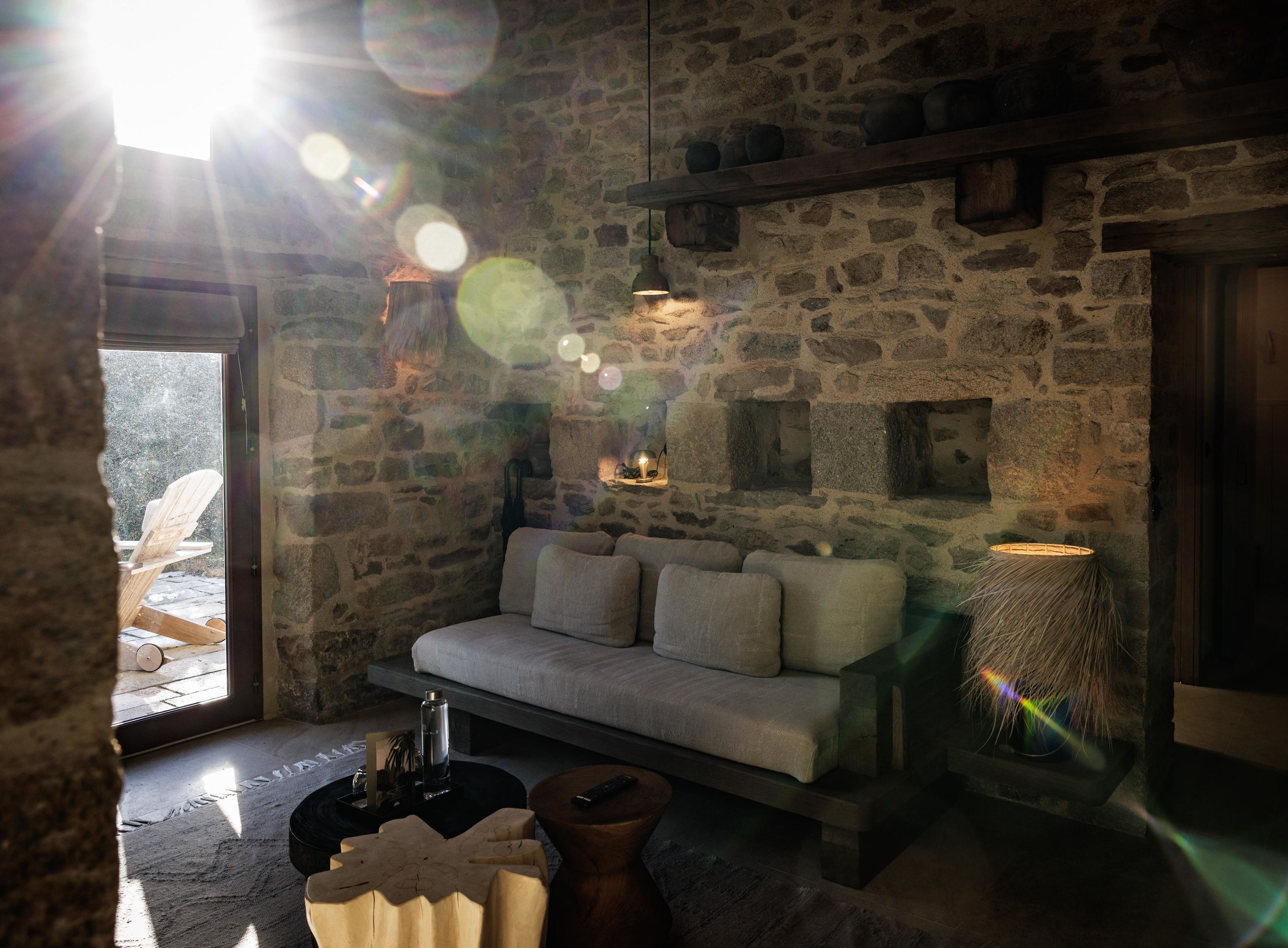 A cozy stone-floored room with a sofa, a small table, and a lamp.