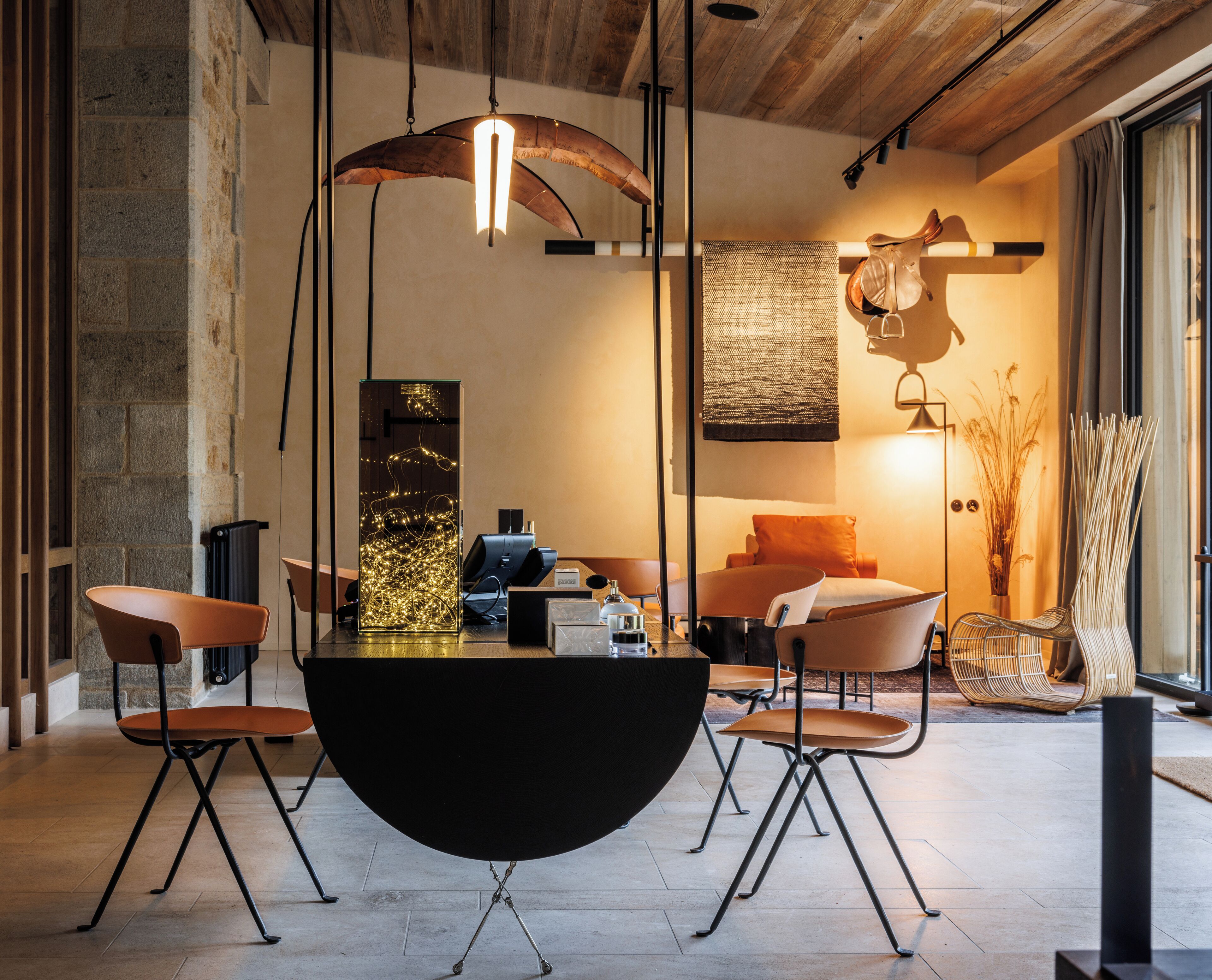 Un espace repas moderne avec une table ronde noire, quatre chaises et un luminaire suspendu.