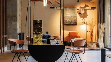 Un espace repas moderne avec une table ronde noire, quatre chaises et un luminaire suspendu.