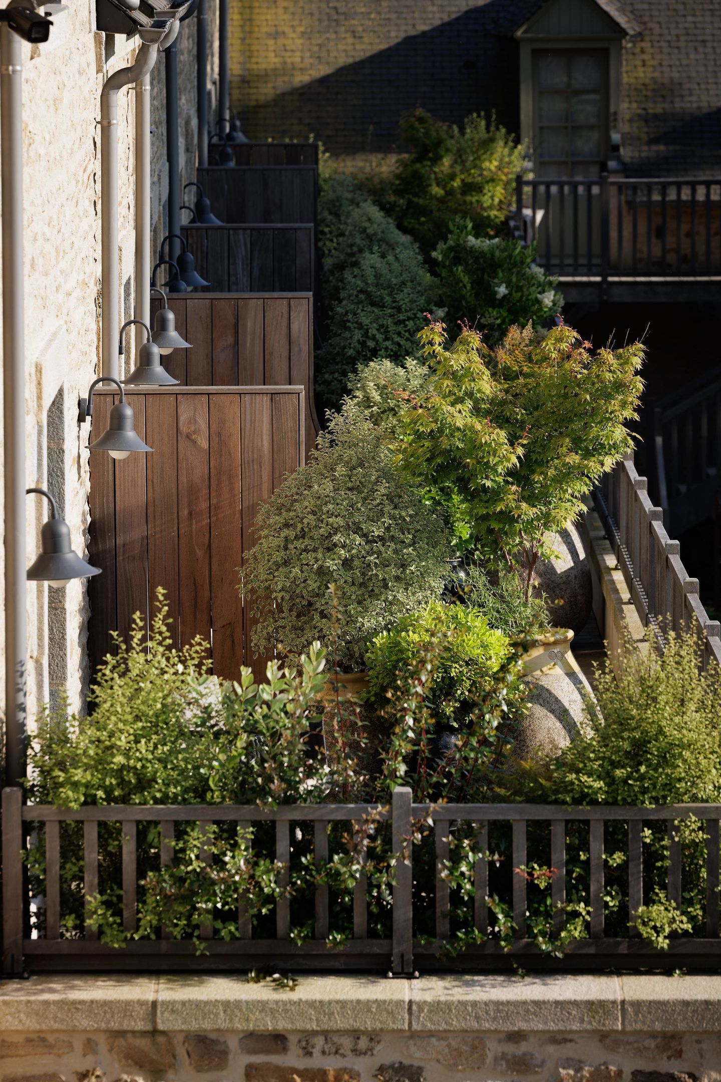 A wooden fence with a stone wall, a wooden gate, and a potted plant.