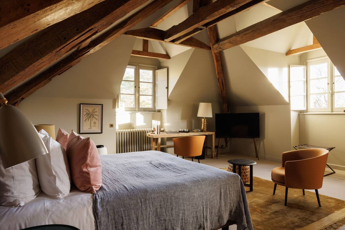 A bedroom with a bed, a desk, a chair, and a television.
