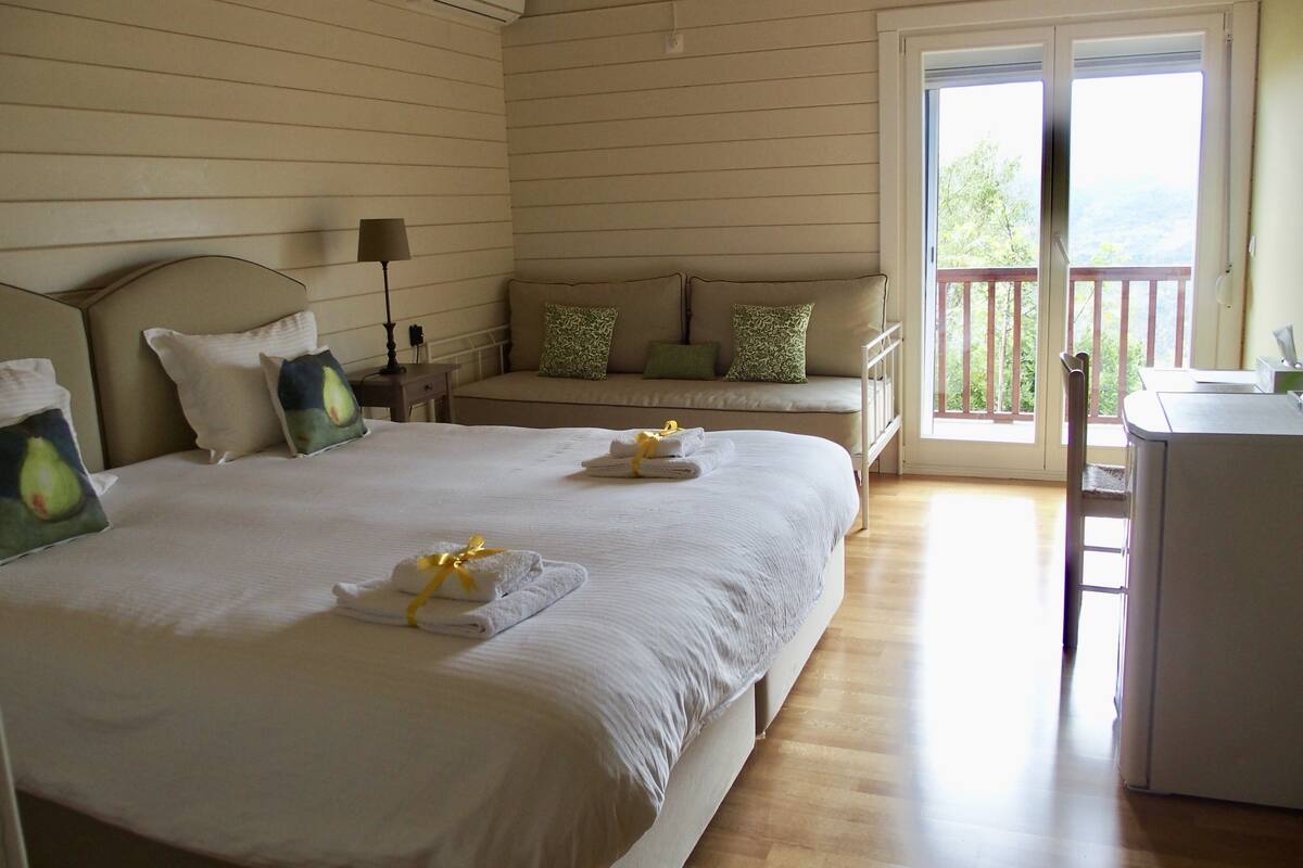 Ein Schlafzimmer mit zwei Betten, einer Couch, einem Schreibtisch und einem Balkon.