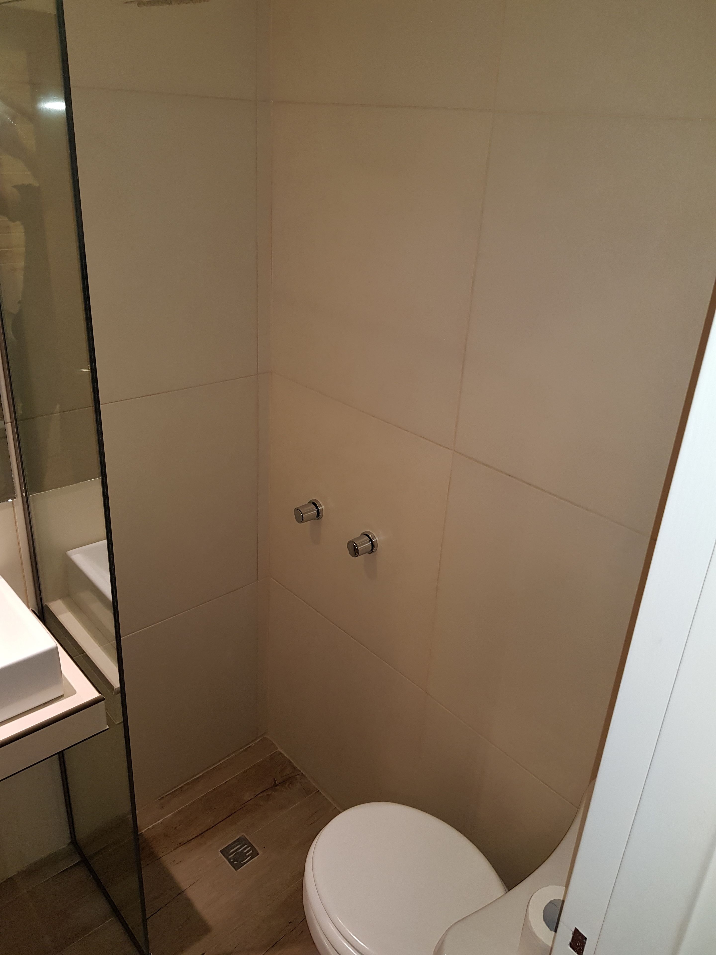 Un baño pequeño y moderno con cabina de ducha de vidrio, inodoro blanco y lavamanos.