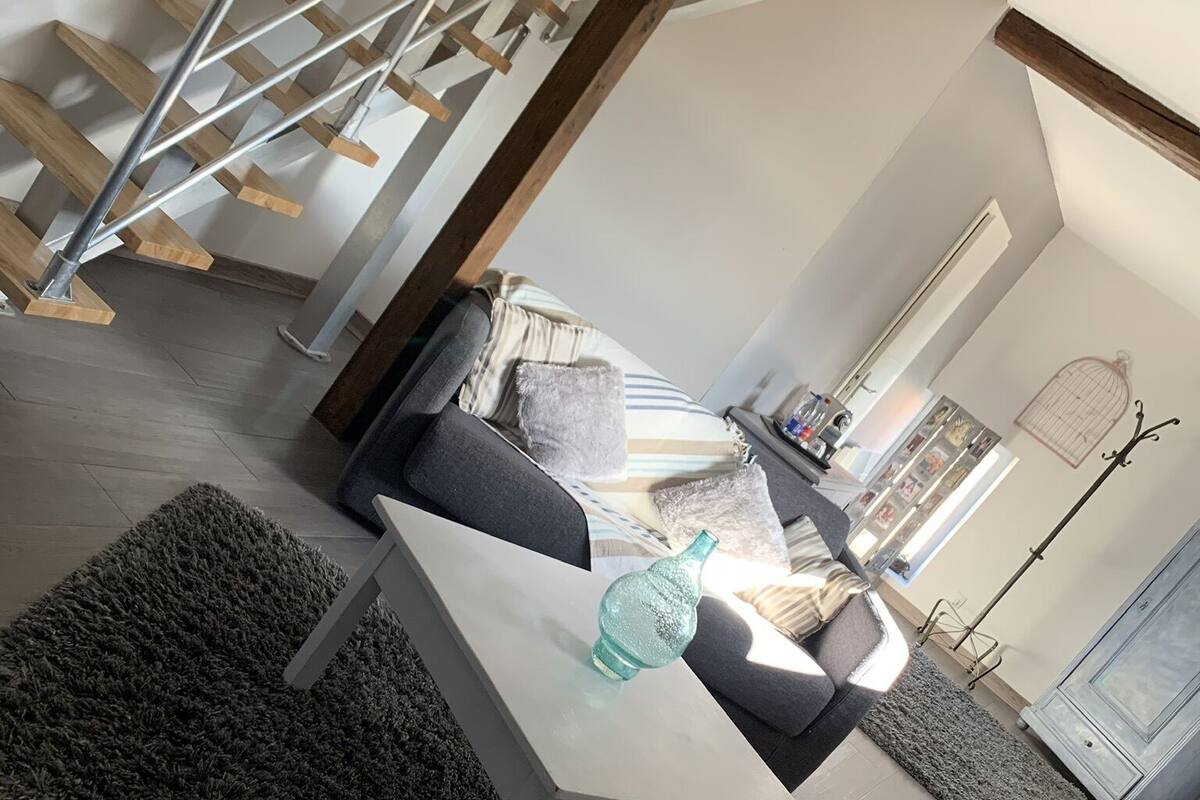 A modern living room with a staircase, a dining table with chairs, and a sofa.