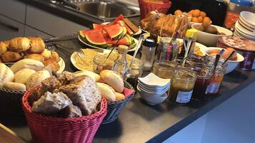 A buffet with various breads, pastries, and condiments.