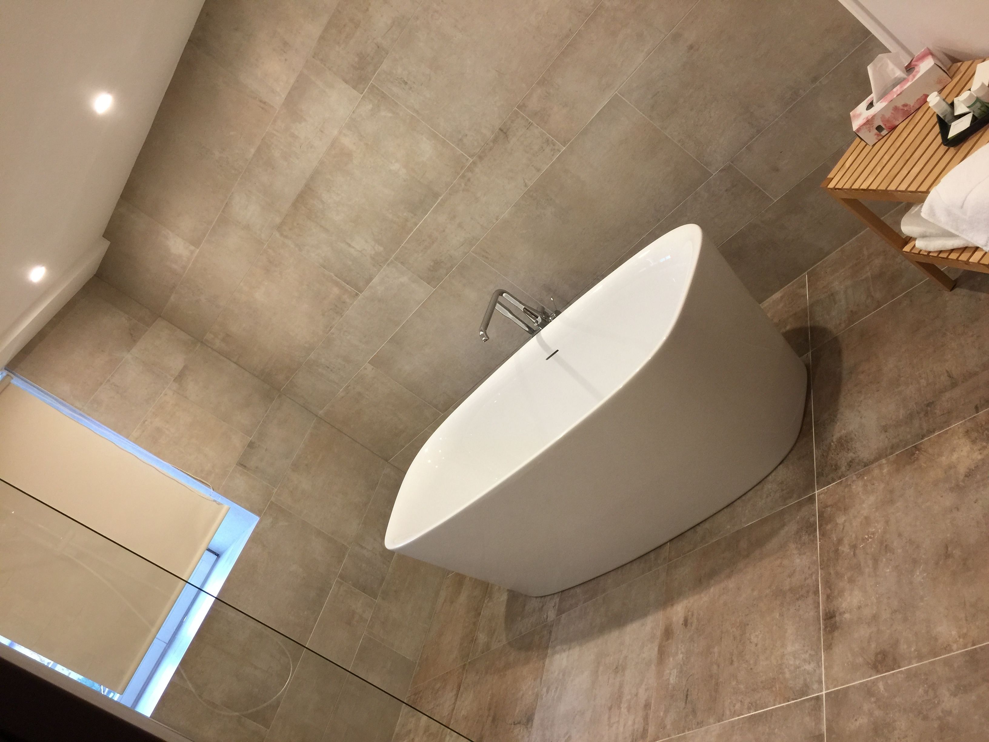 A modern bathroom with a freestanding bathtub, a wooden vanity, and a towel rack.
