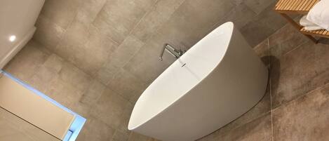 A modern bathroom with a freestanding bathtub, a wooden vanity, and a towel rack.