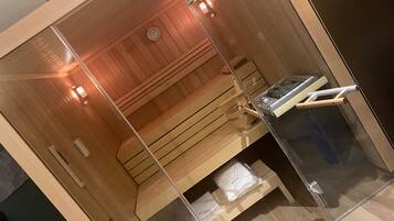 Un sauna avec un banc en bois, un appareil de chauffage pour sauna et une paroi en verre.