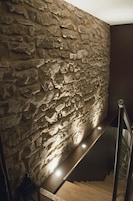 Una escalera con un muro de piedra a un lado y piso de madera.