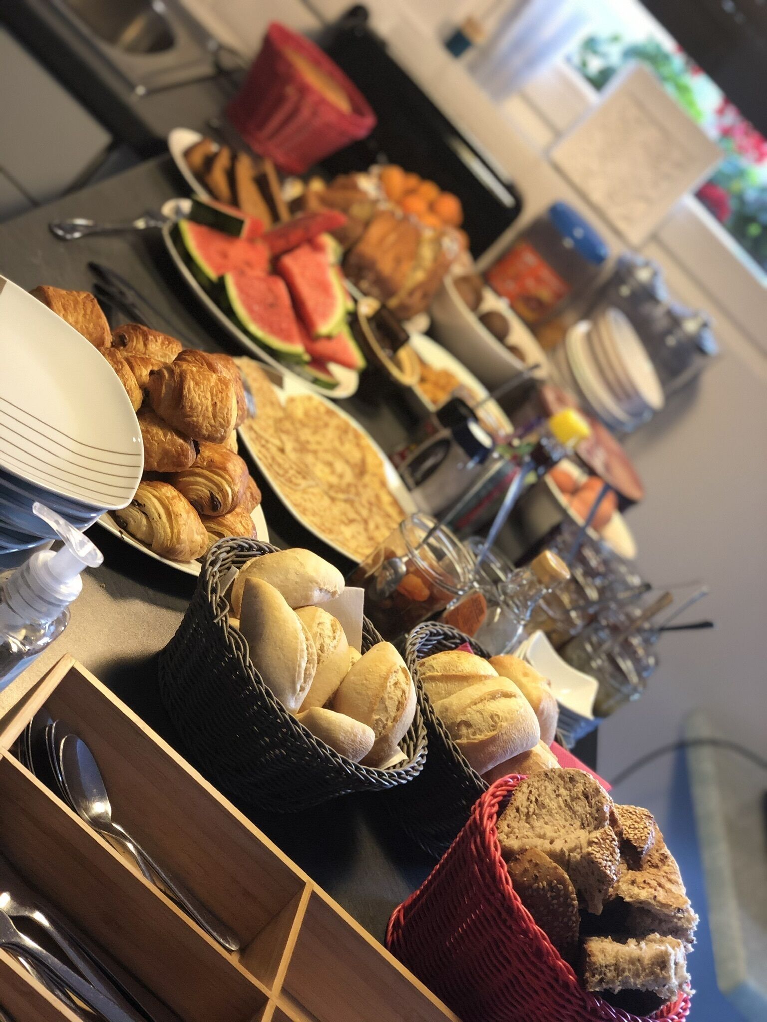 Une table de buffet proposant divers aliments, notamment du pain, des pâtisseries et des fruits.