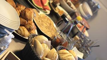 Une table de buffet proposant divers aliments, notamment du pain, des pâtisseries et des fruits.