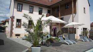 A two-story building with a balcony, outdoor seating area with umbrellas, and a wooden deck. - L'Ecurie d'Obernai (Obernai)