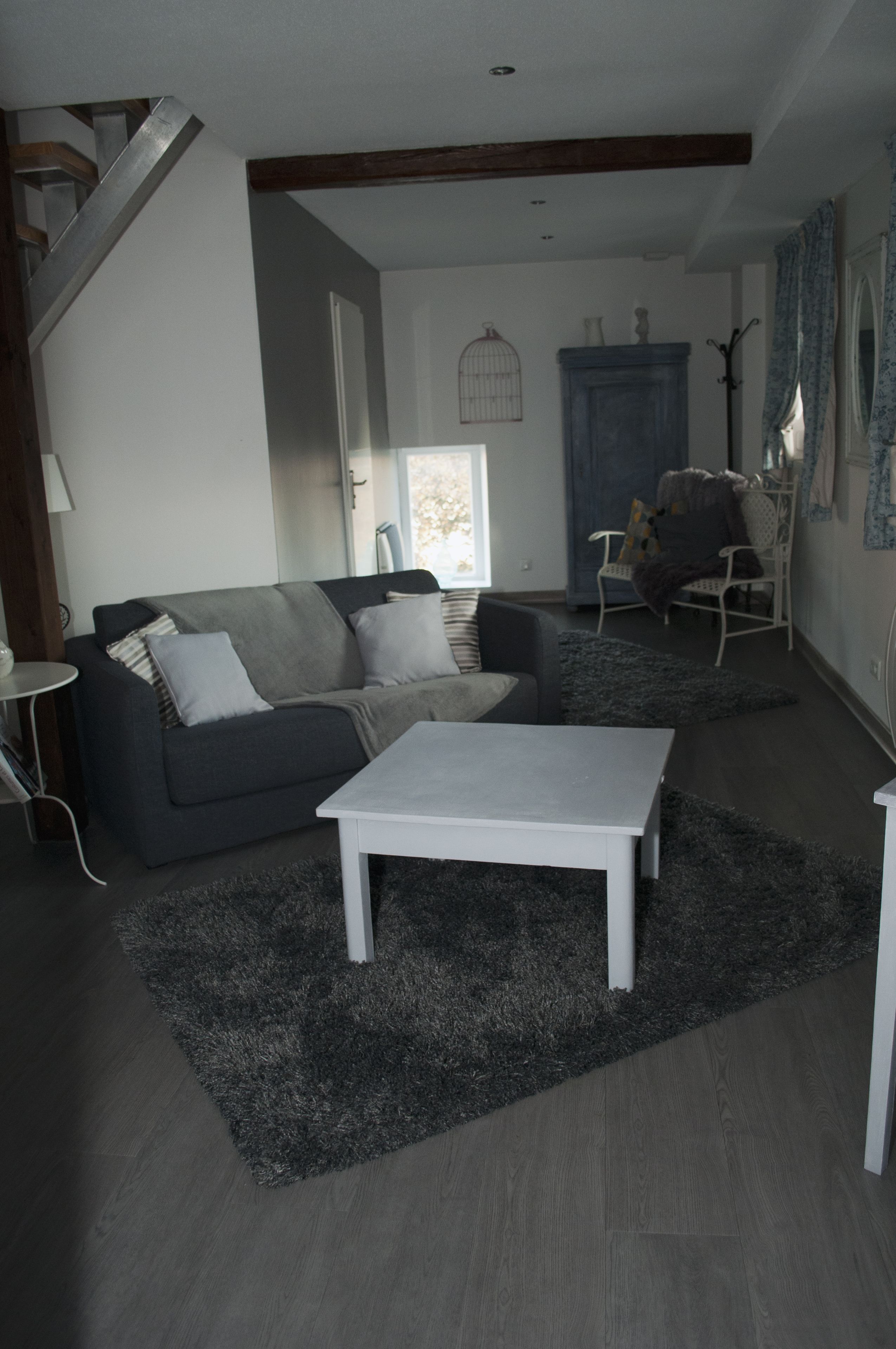 En moderne stue med en grå sofa, et hvidt sofabord og en grå plys-løber.