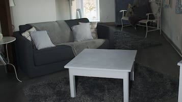 En moderne stue med en grå sofa, et hvidt sofabord og en grå plys-løber.