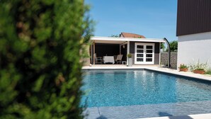 A swimming pool with a covered patio area, a stone wall, and potted plants. - L'Ecurie d'Obernai (Obernai)