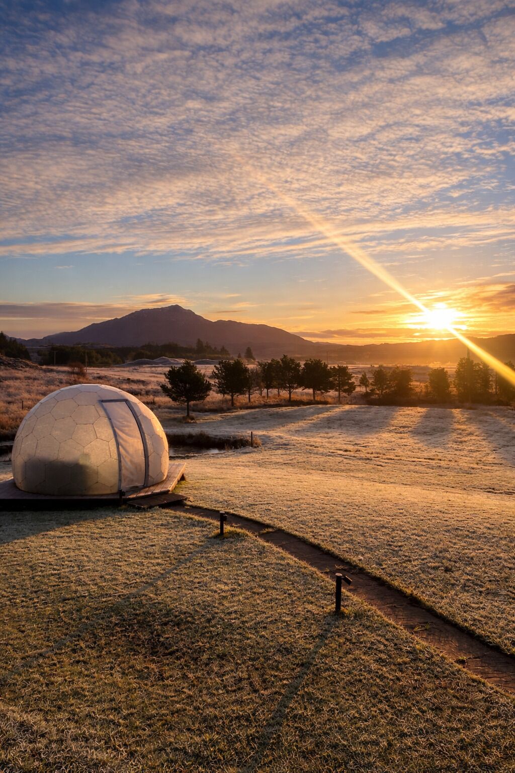 A spherical structure in a field with a sunset in the background.