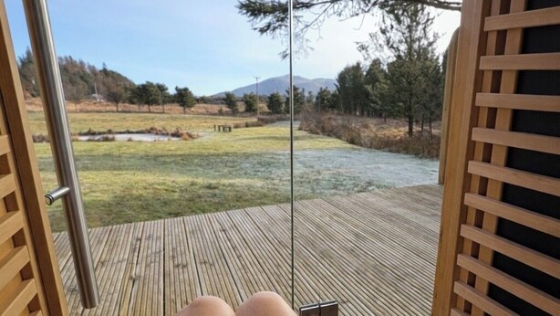Una terraza de madera con vistas a un campo cubierto de hierba y árboles.