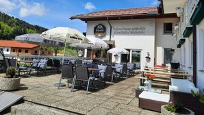 Un café al aire libre con mesas y sillas, sombrillas y un edificio con un letrero.