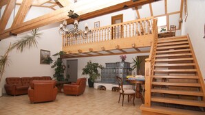 Amplia sala de estar con techo alto, escalera de madera y balcón.