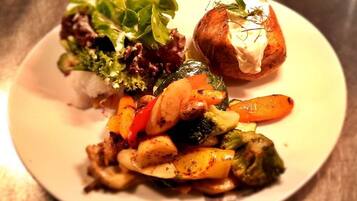 A plate with a salad, roasted vegetables, and a bread roll.