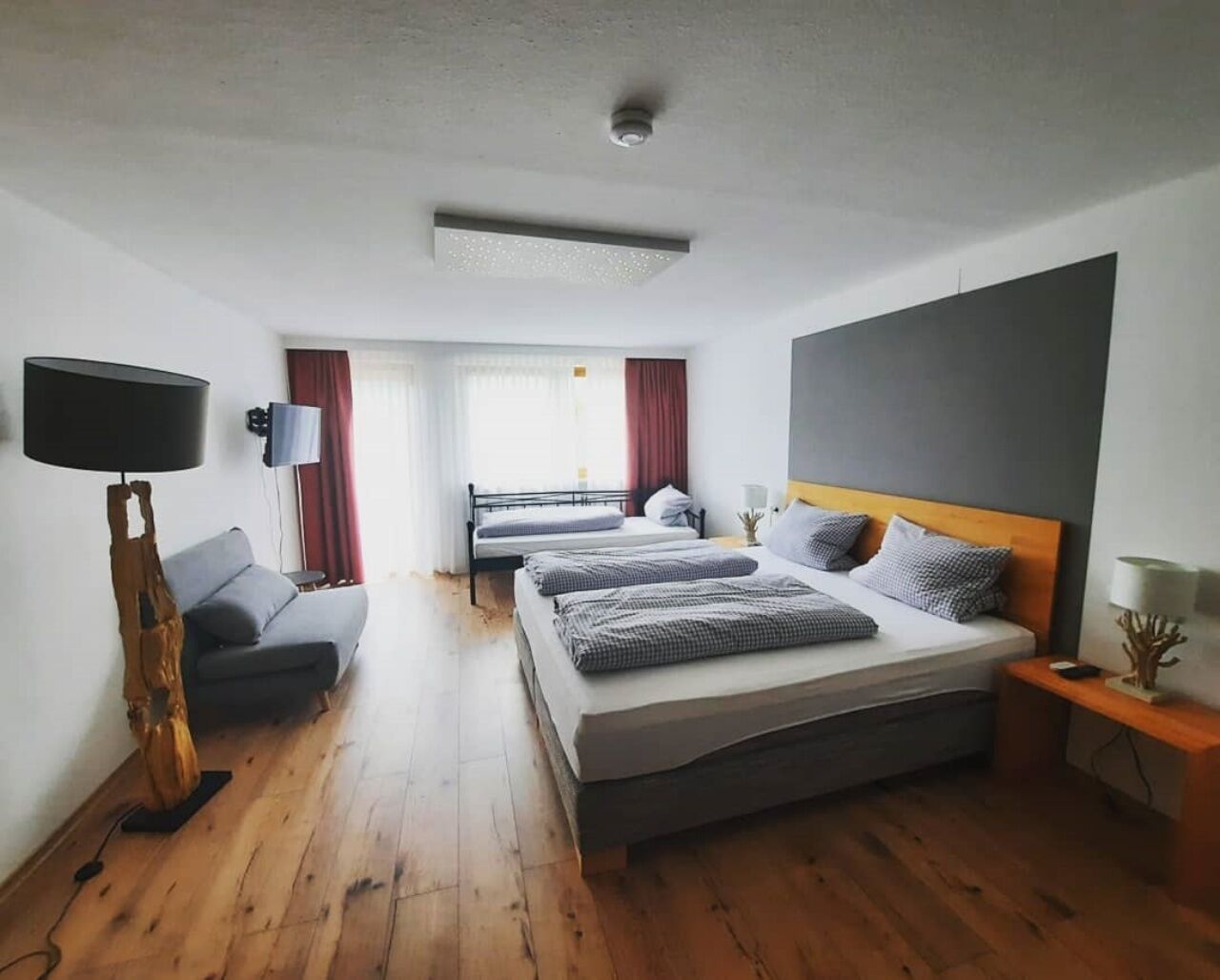 Una habitación de hotel moderna con una cama grande, un sofá, un televisor y un escritorio.